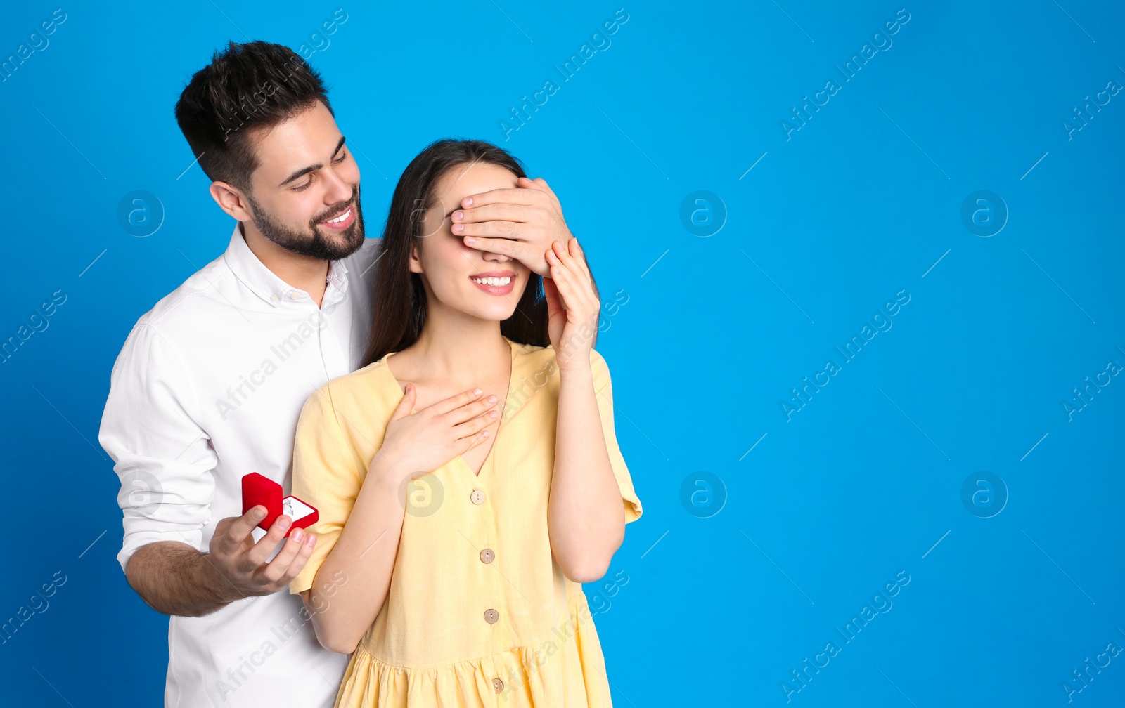 Photo of Man with engagement ring making marriage proposal to girlfriend on blue background