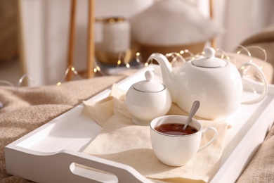 Photo of White tray with ceramic tea set on bed