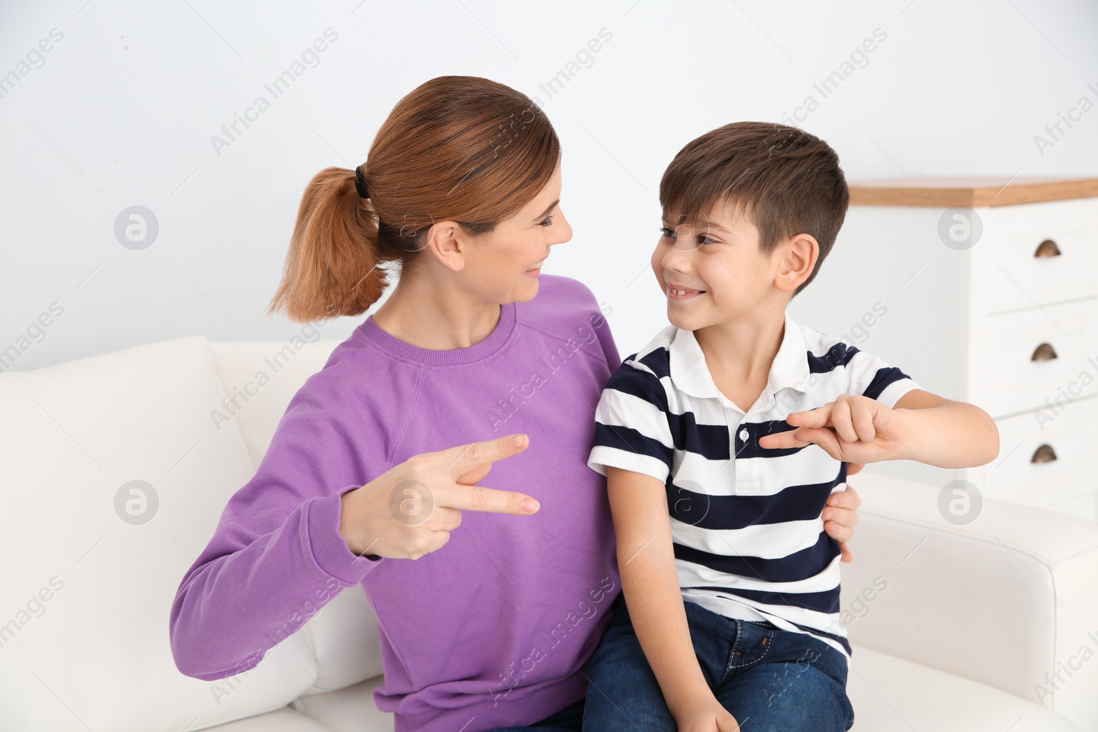 Photo of Hearing impaired mother and her child talking with help of sign language indoors