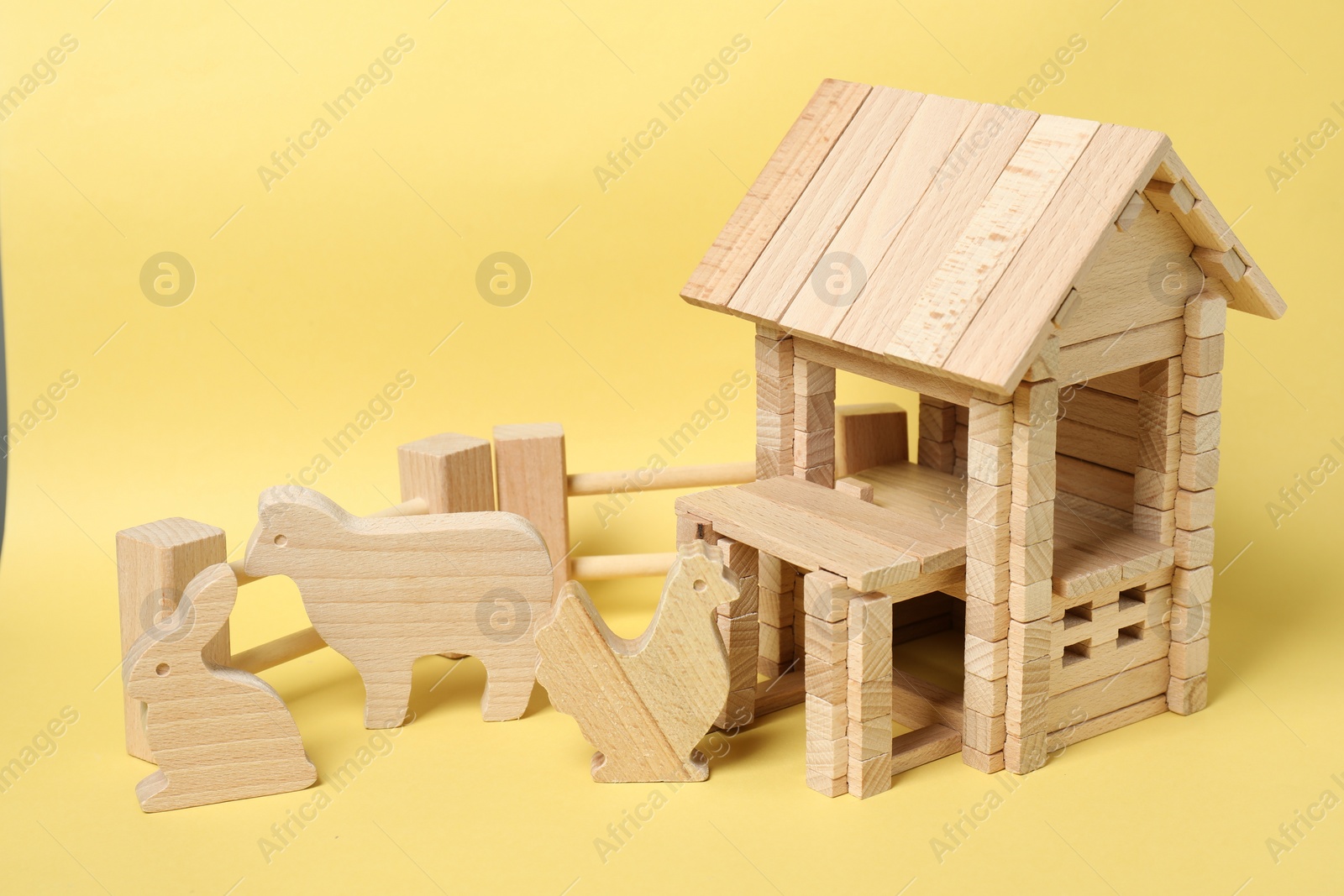 Photo of Wooden house and animals on yellow background. Children's toy