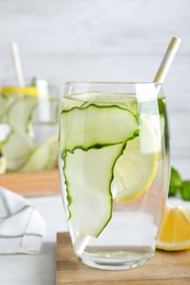 Refreshing water with cucumber, lemon and mint on white table, closeup
