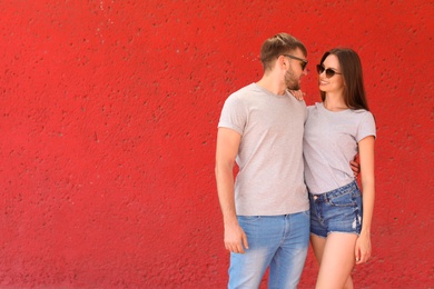 Photo of Young couple wearing gray t-shirts near color wall on street