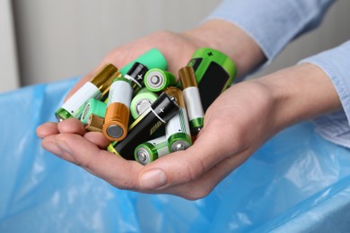 Woman holding many used electric batteries in her hands, closeup