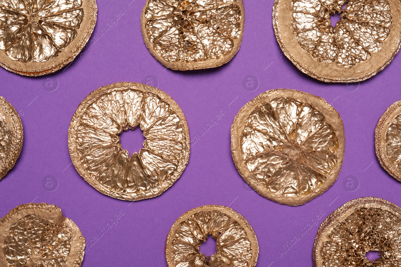 Photo of Golden lemon slices on purple background, flat lay