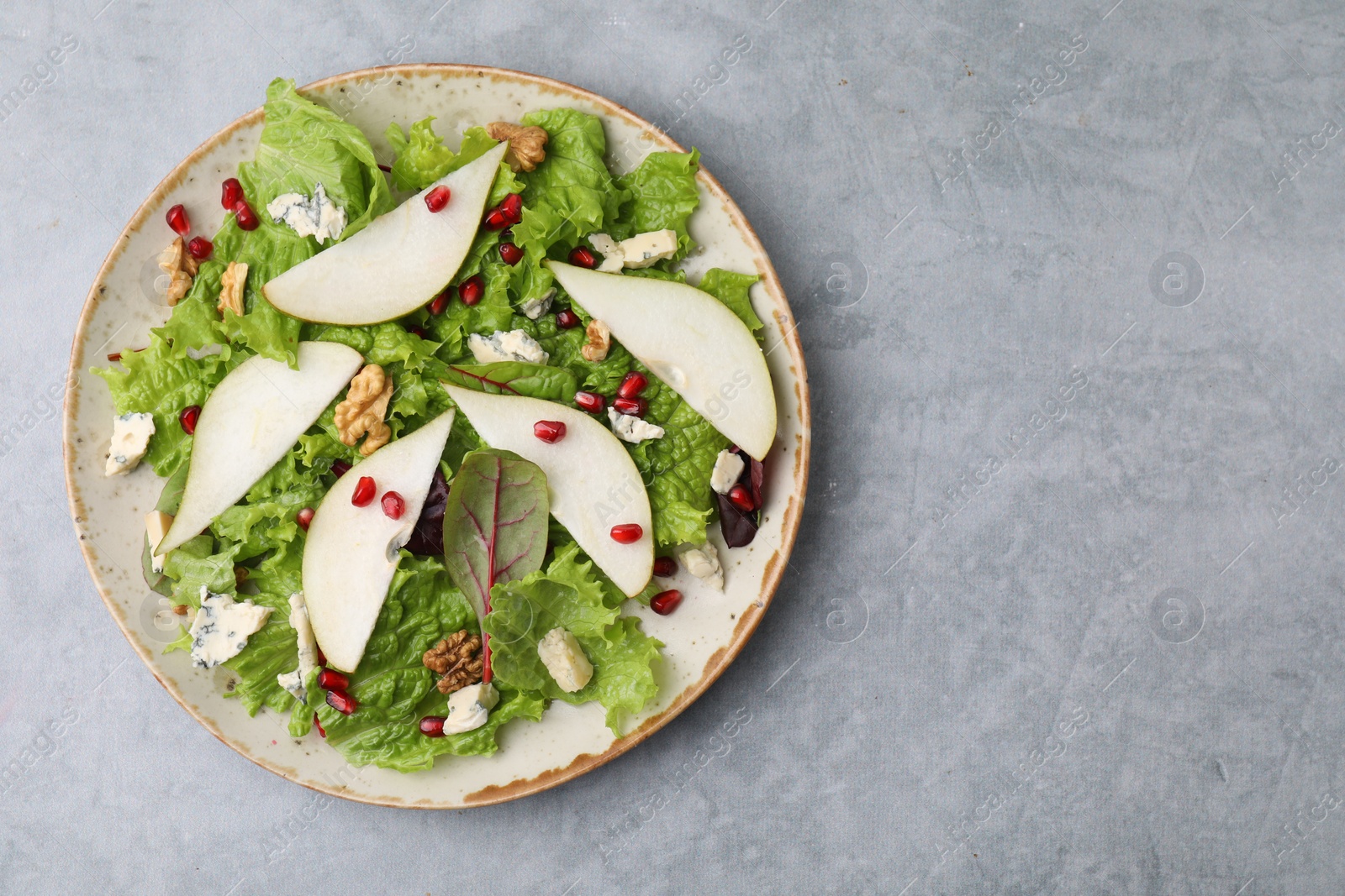 Photo of Plate with delicious pear salad on grey textured table, top view. Space for text