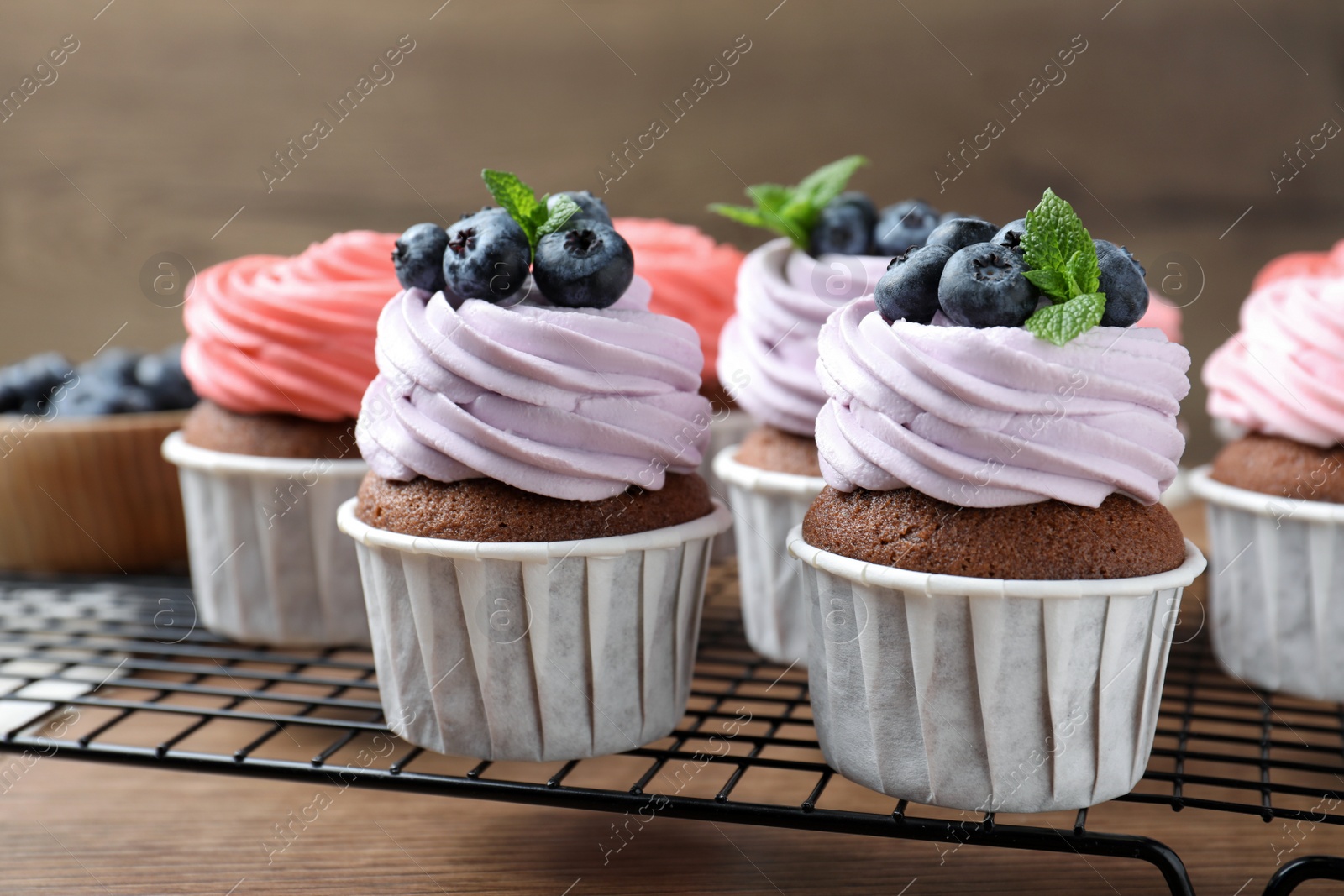 Photo of Sweet cupcakes with fresh blueberries on wooden table, closeup