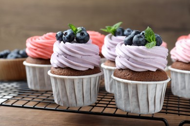 Photo of Sweet cupcakes with fresh blueberries on wooden table, closeup