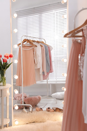 Photo of Rack with stylish women's clothes and mirror indoors. Interior design