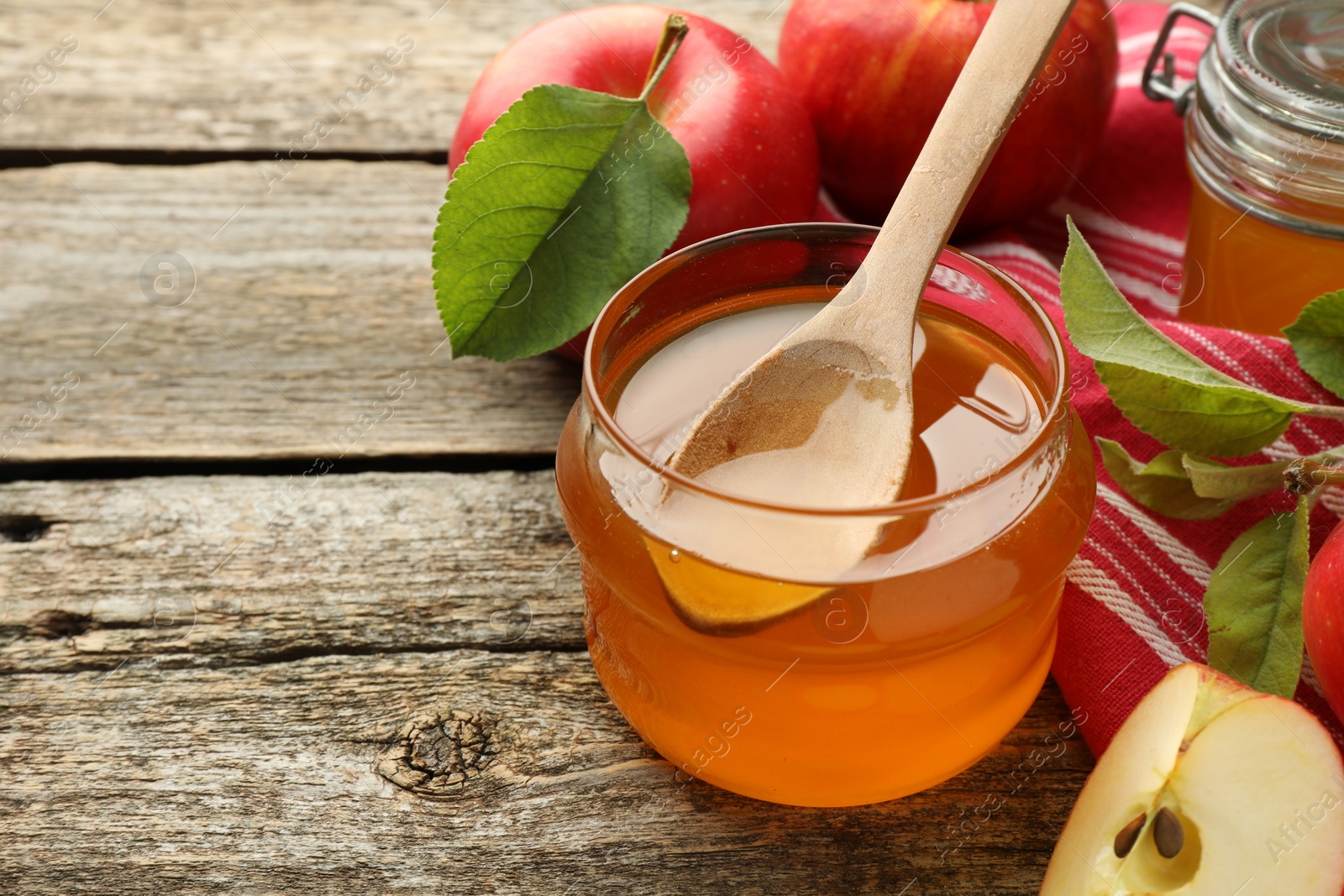 Photo of Sweet honey and fresh apples on wooden table, closeup. Space for text