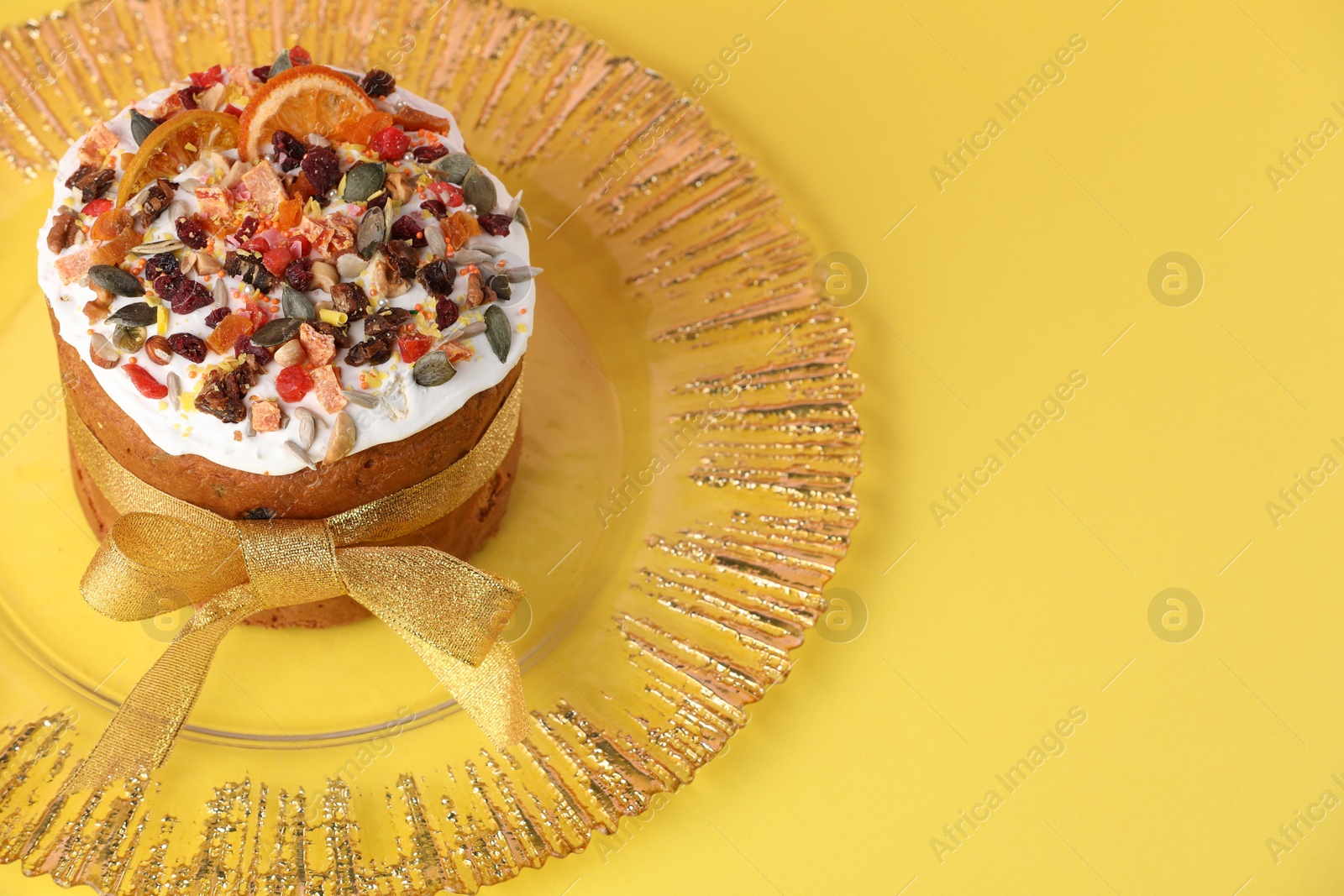 Photo of Traditional Easter cake with dried fruits on yellow background. Space for text