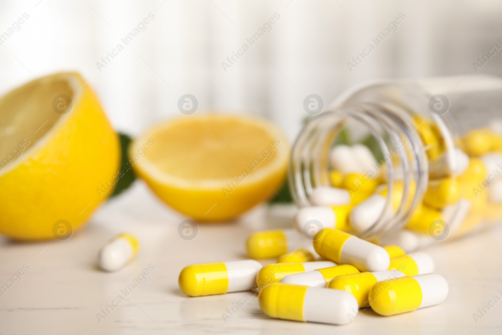 Photo of Bottle with vitamin pills and lemon on light table, closeup