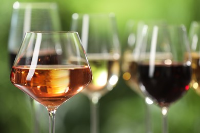 Photo of Different tasty wines in glasses against blurred background, closeup. Space for text