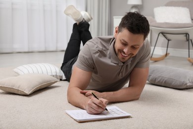 Man solving sudoku puzzle on floor at home