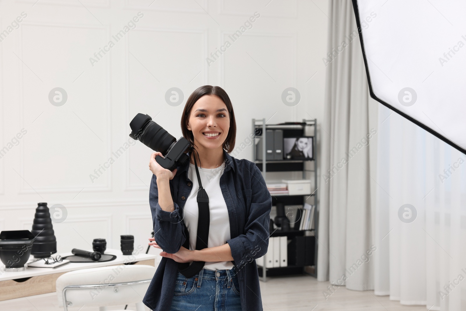 Photo of Young professional photographer with camera in modern photo studio