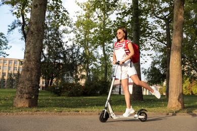 Young woman riding electric kick scooter in park