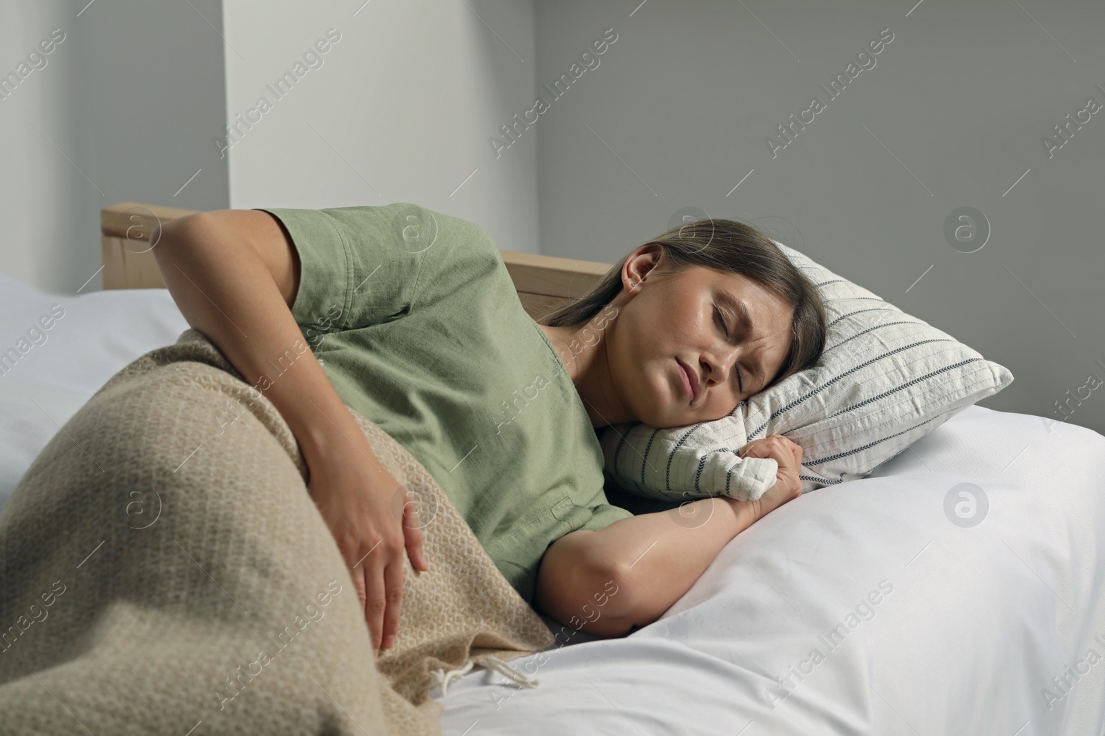 Photo of Young woman suffering from menstrual pain in bed at home