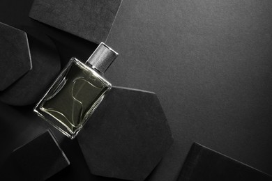 Stylish presentation of luxury men`s perfume in bottle on black background, top view. Space for text