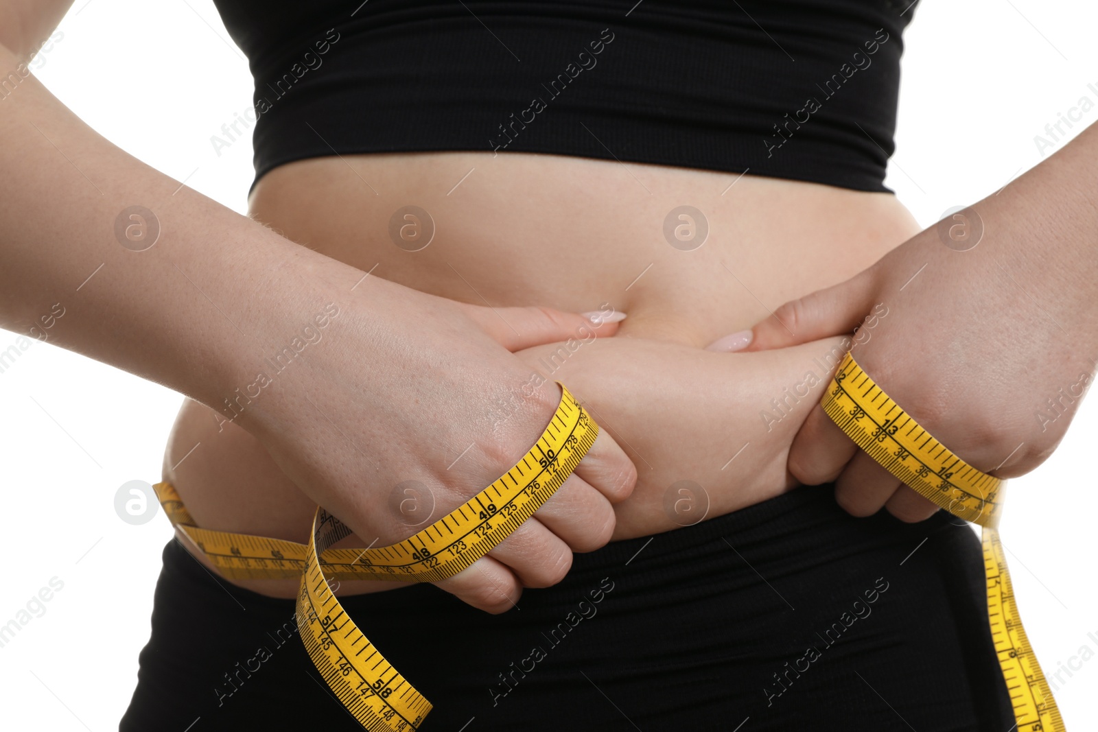 Photo of Woman with measuring tape touching belly fat on white background, closeup. Overweight problem