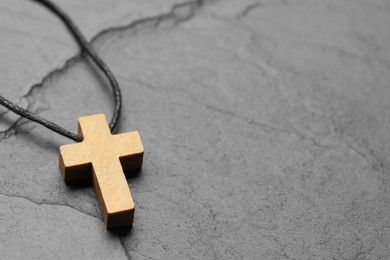 Wooden Christian cross on black table, closeup. Space for text