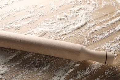 Scattered flour and rolling pin on wooden table, closeup