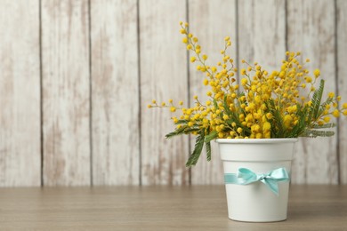 Photo of Bouquet of beautiful mimosa flowers on wooden table. Space for text