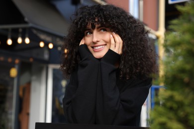 Photo of Happy young woman in stylish black sweater outdoors