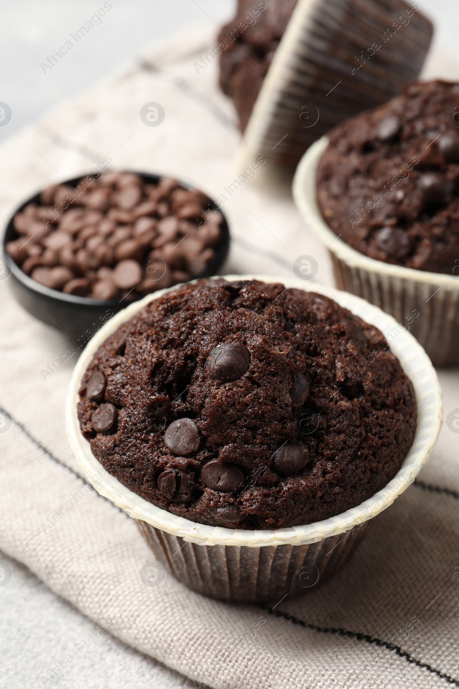 Photo of Tasty chocolate muffins and cloth on table, closeup