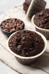 Tasty chocolate muffins and cloth on table, closeup