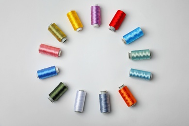 Photo of Composition with color sewing threads on white background, top view