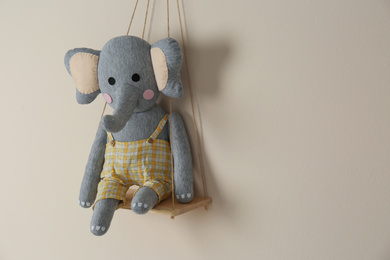 Shelf with cute toy elephant on beige wall, space for text. Child's room interior element