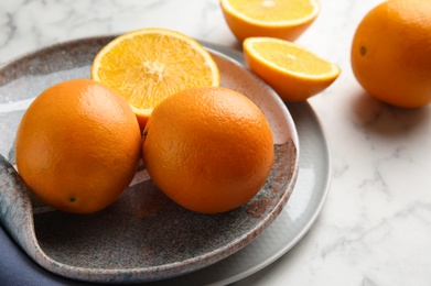 Plate with fresh juicy oranges on marble table