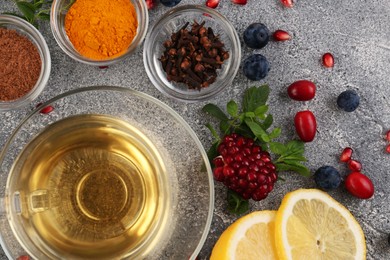 Photo of Cup with delicious immunity boosting tea and ingredients on grey table, flat lay