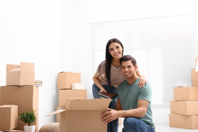 Photo of Happy couple unpacking cardboard boxes in their new flat on moving day
