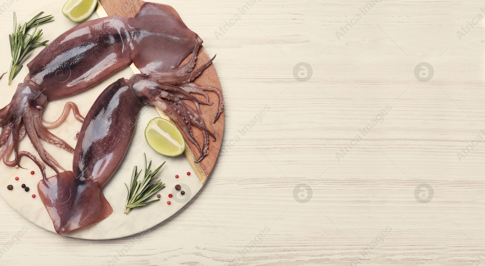 Image of Board with fresh squids, slices of lime and rosemary on wooden table, flat lay. Banner design with space for text