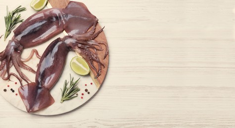 Image of Board with fresh squids, slices of lime and rosemary on wooden table, flat lay. Banner design with space for text