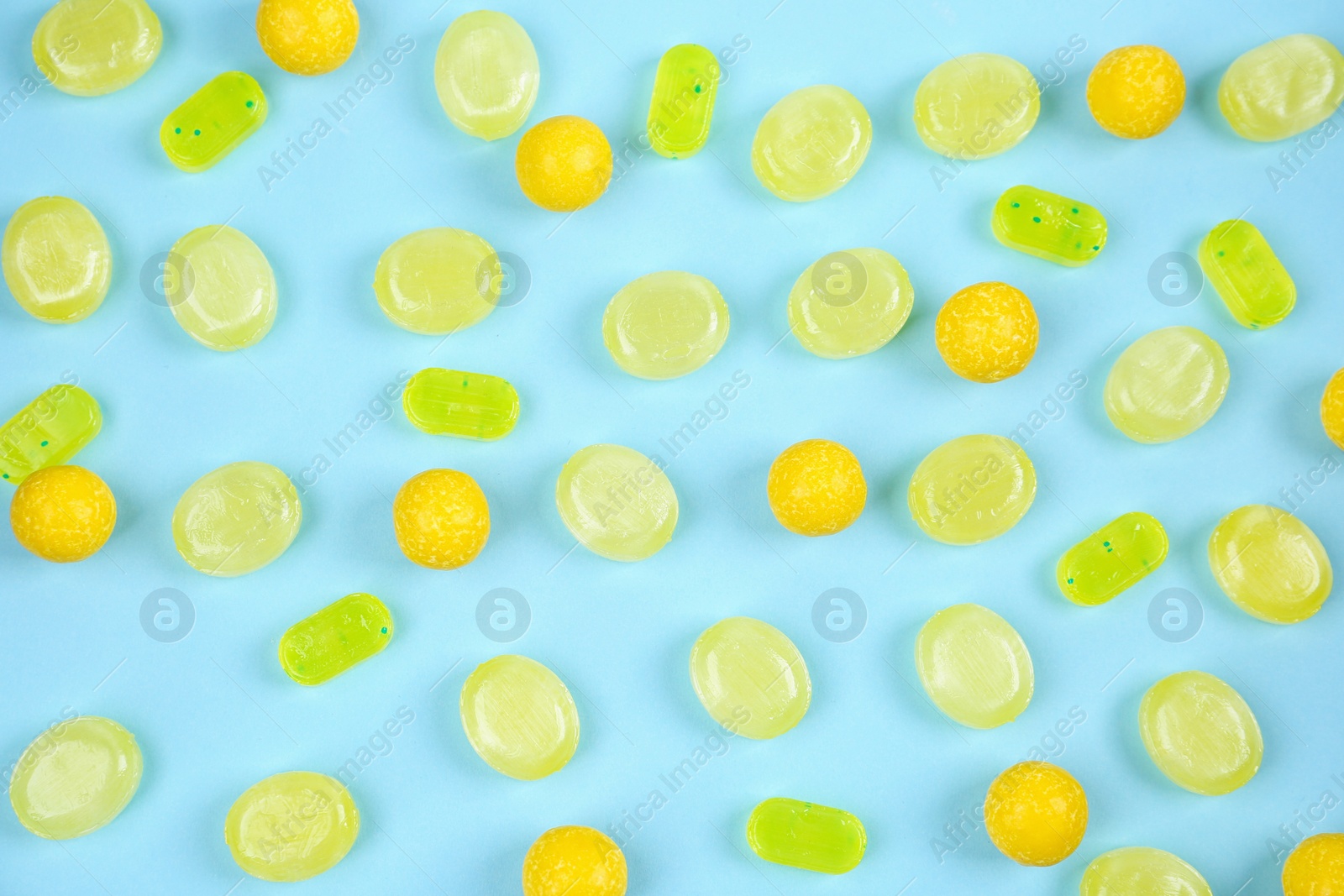 Photo of Delicious lemon candies on light blue background, flat lay