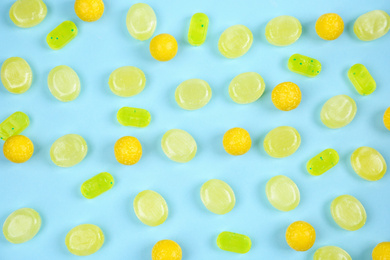 Photo of Delicious lemon candies on light blue background, flat lay