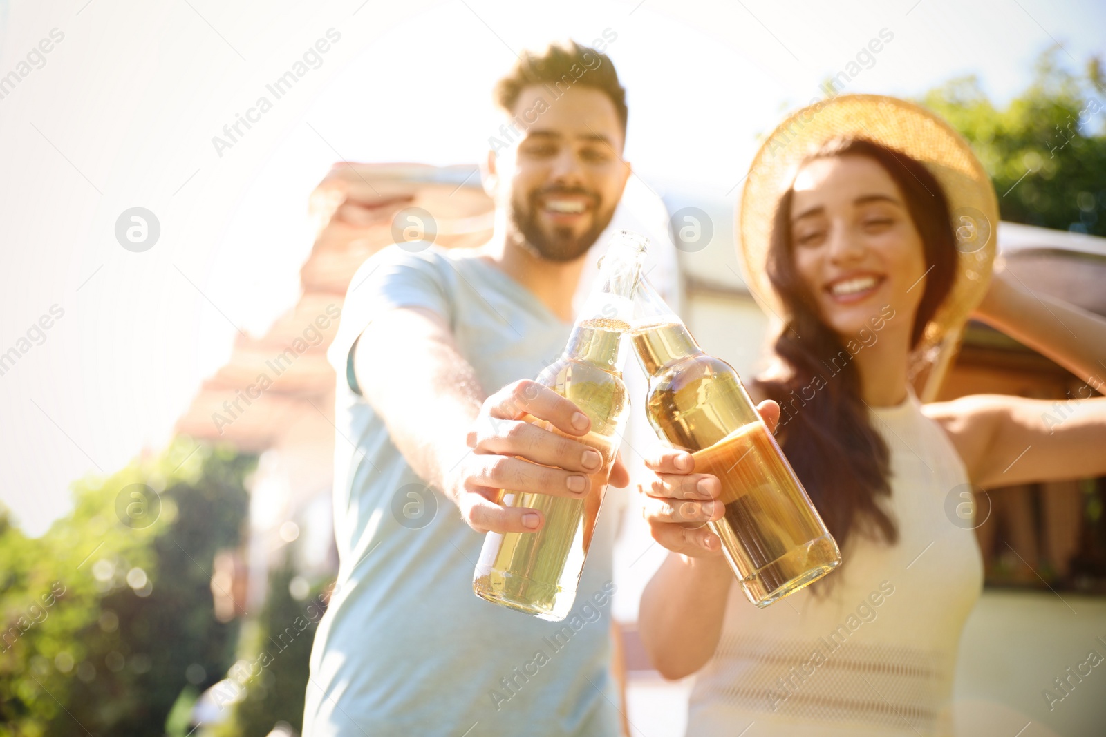 Photo of Young couple with bottles of beer outdoors, focus on hands. Camping season