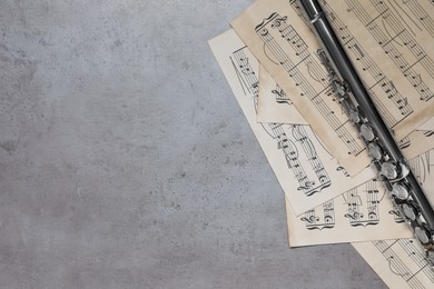 Sheets with musical notes and flute on grey table, flat lay. Space for text