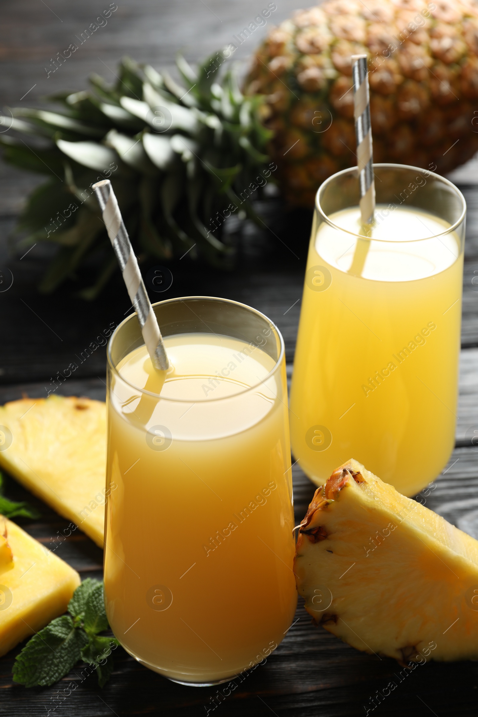 Photo of Delicious pineapple juice and fresh fruit on black wooden table, closeup