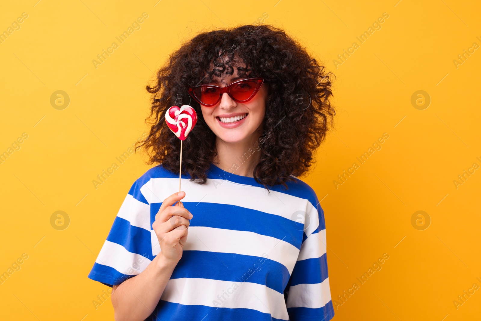 Photo of Beautiful woman in sunglasses with lollipop on yellow background