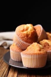 Photo of Delicious sweet muffins on wooden table against dark background, closeup