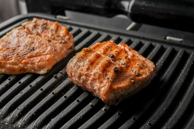 Photo of Tasty salmon cooking on electric grill, closeup