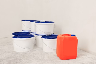 Photo of Buckets with paint and canister of primer on floor indoors
