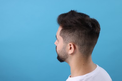 Man with healthy hair on light blue background, space for text