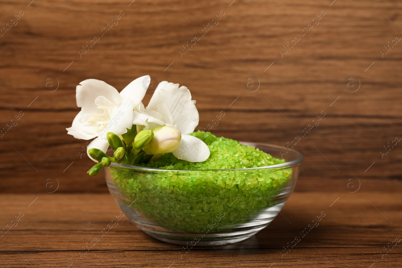 Photo of Aromatic sea salt and flowers on wooden table, closeup