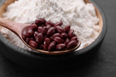 Photo of Kidney bean flour and seeds on dark table, closeup