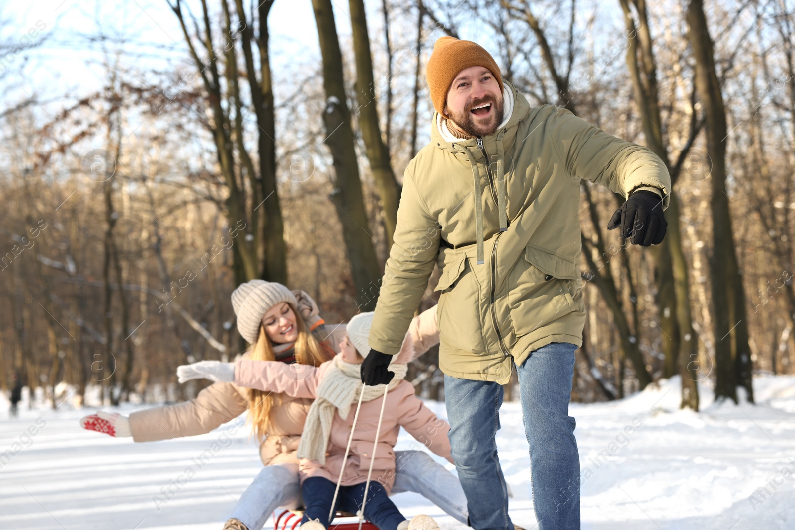 Photo of Happy family having fun with sledge in snowy forest