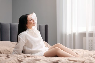 Photo of Beautiful woman sitting on bed at home, space for text. Lazy morning
