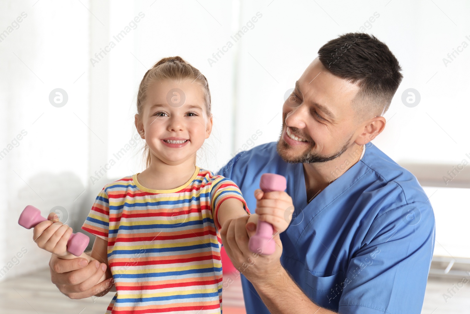 Photo of Orthopedist working with little girl in hospital gym